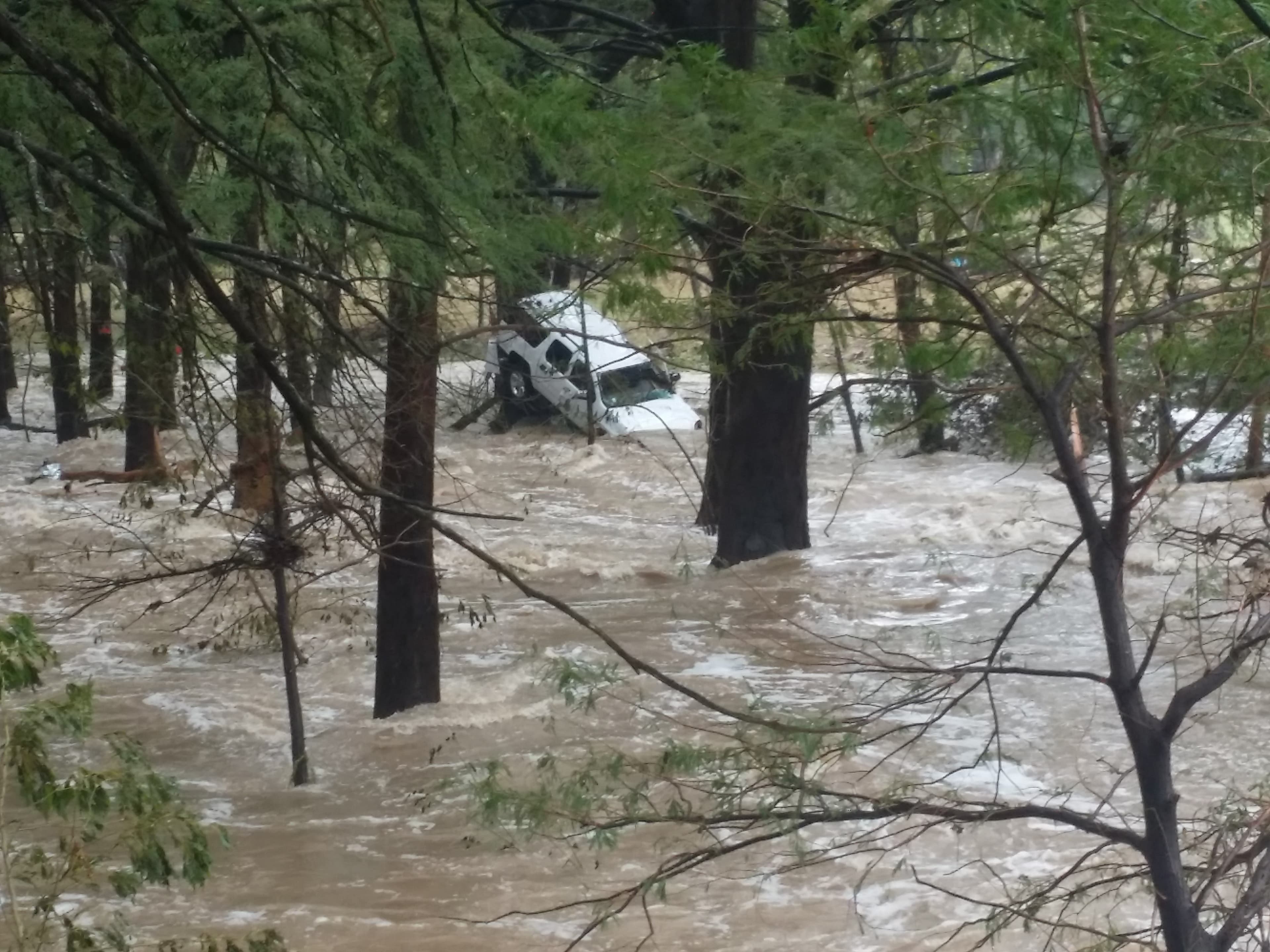 A pickup truck swept off the road and pinned against trees by raging flash floodwaters in the Texas Hill Country